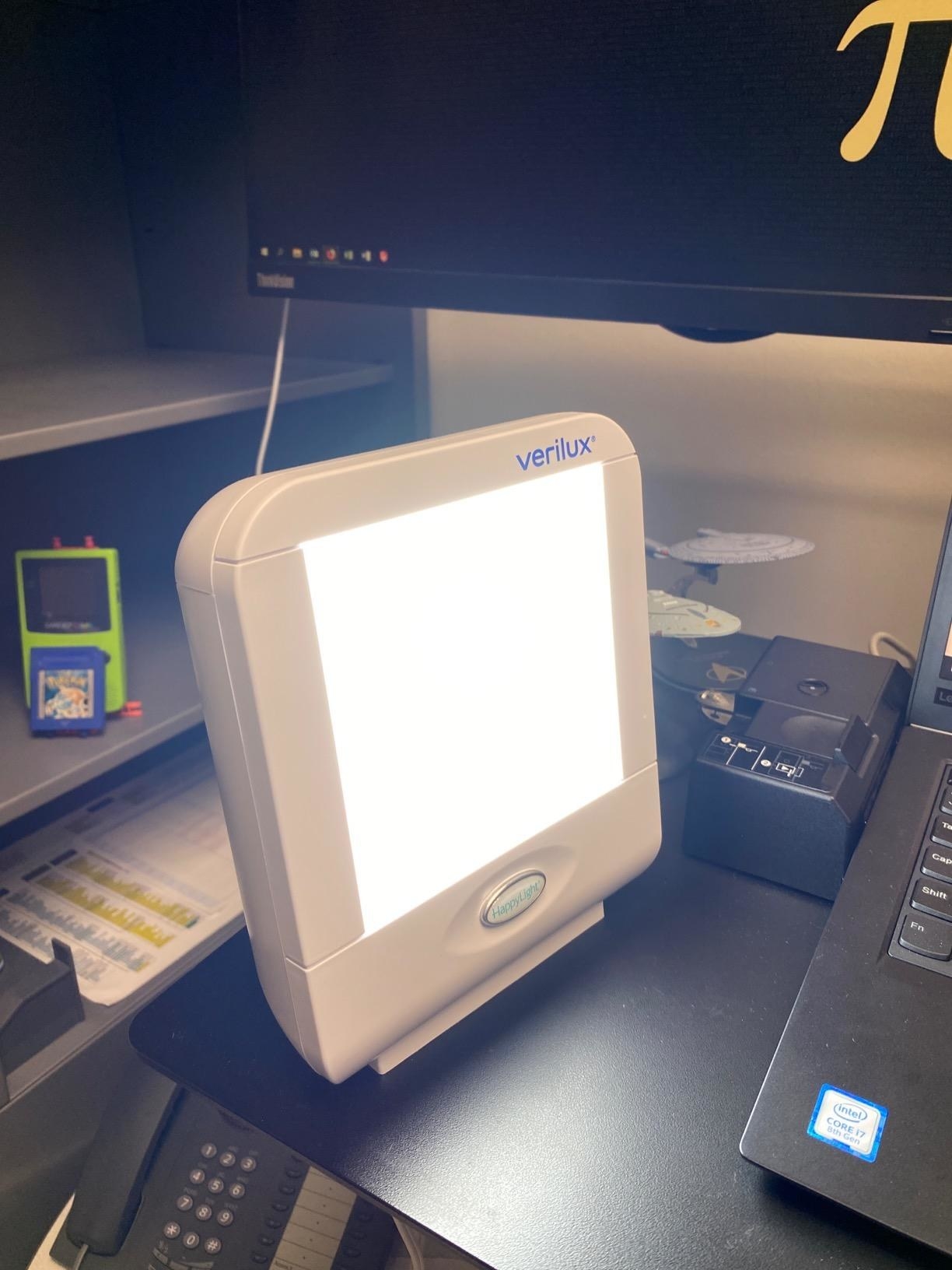 review photo of someones therapy lamp turned on next to their computer