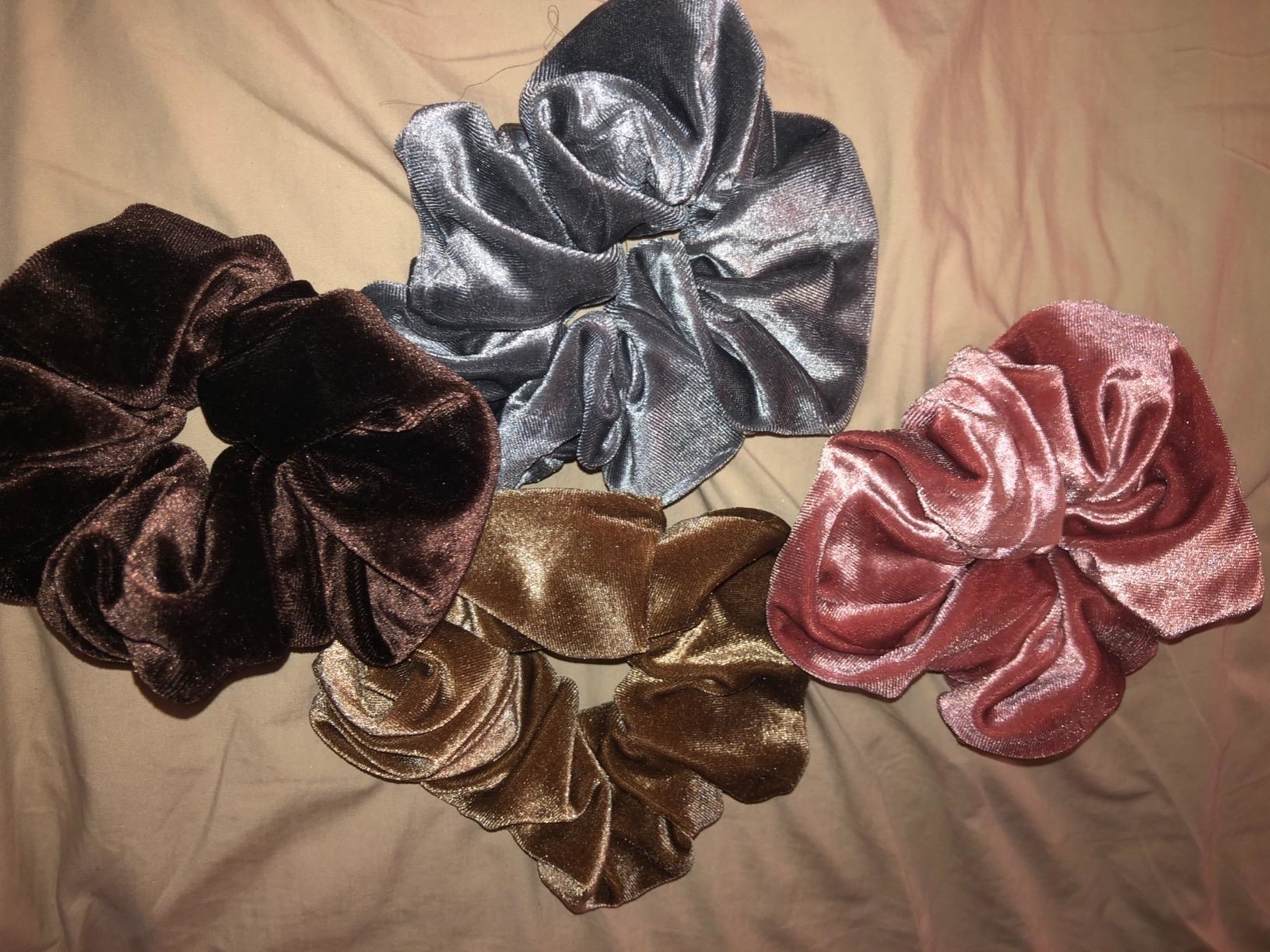the four scrunchies in brown, tan, blue, and pink against a tan background
