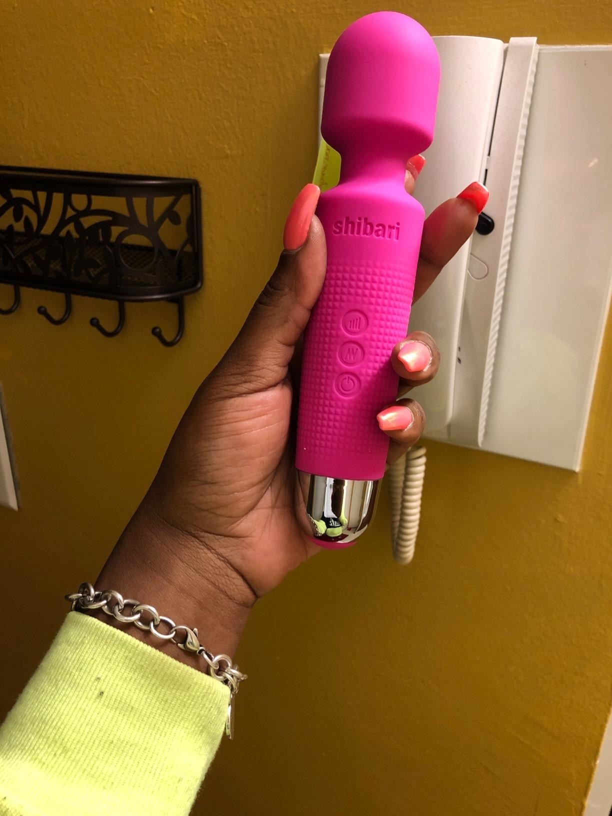 Reviewer holding pink mini wand vibrator
