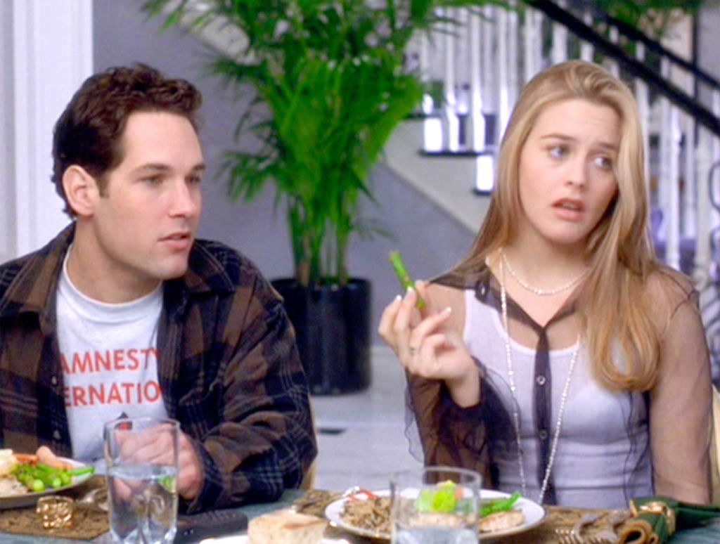 Paul seated at a dinner table next to Alicia Silverstone in a scene from Clueless