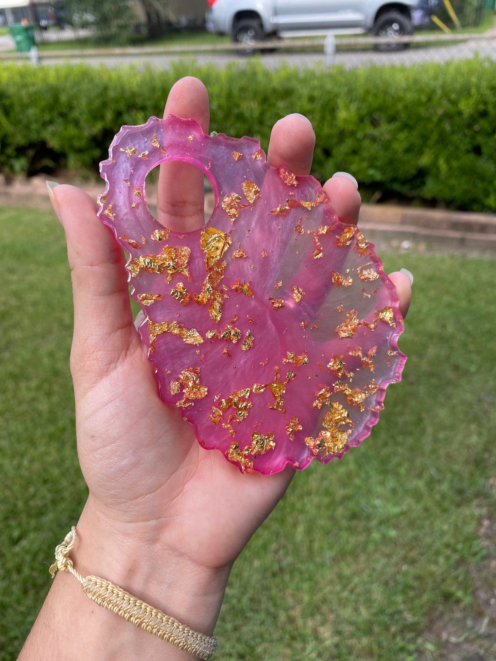 person holding pink and gold flecked resin palette