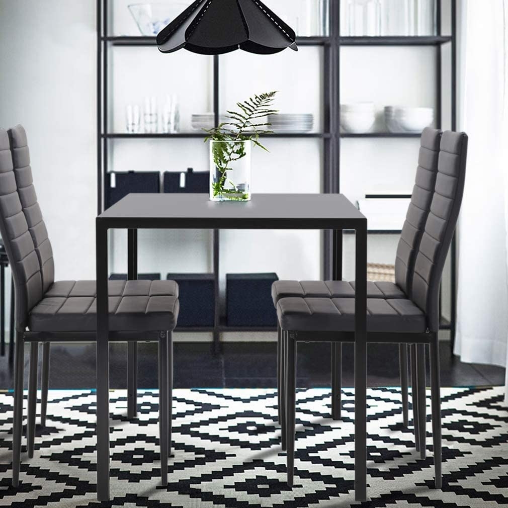 A five-piece dining set with a dining table and four faux leather metal frame chairs