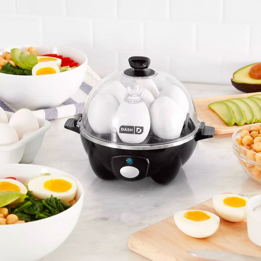 Egg cooker shown filled with eggs, surrounded by food on a countertop