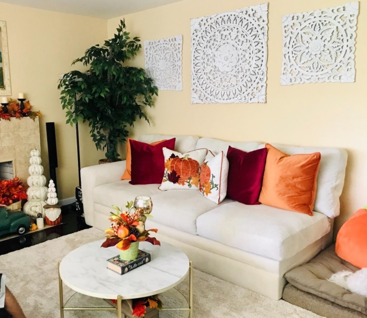 reviewer image of two red and two orange velvet pillow covers on a white couch with pumpkin pillows next to it and other fall decorations around the room