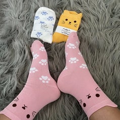 Reviewer wearing the pink cat socks with two other pairs nearby