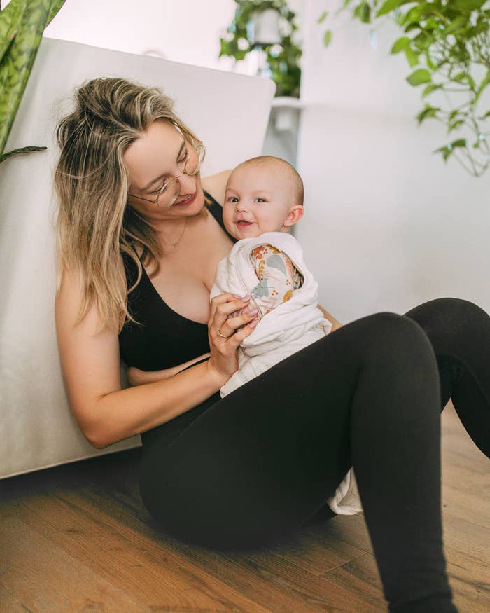 Jo sitting on the floor and holding her smiling baby in her lap