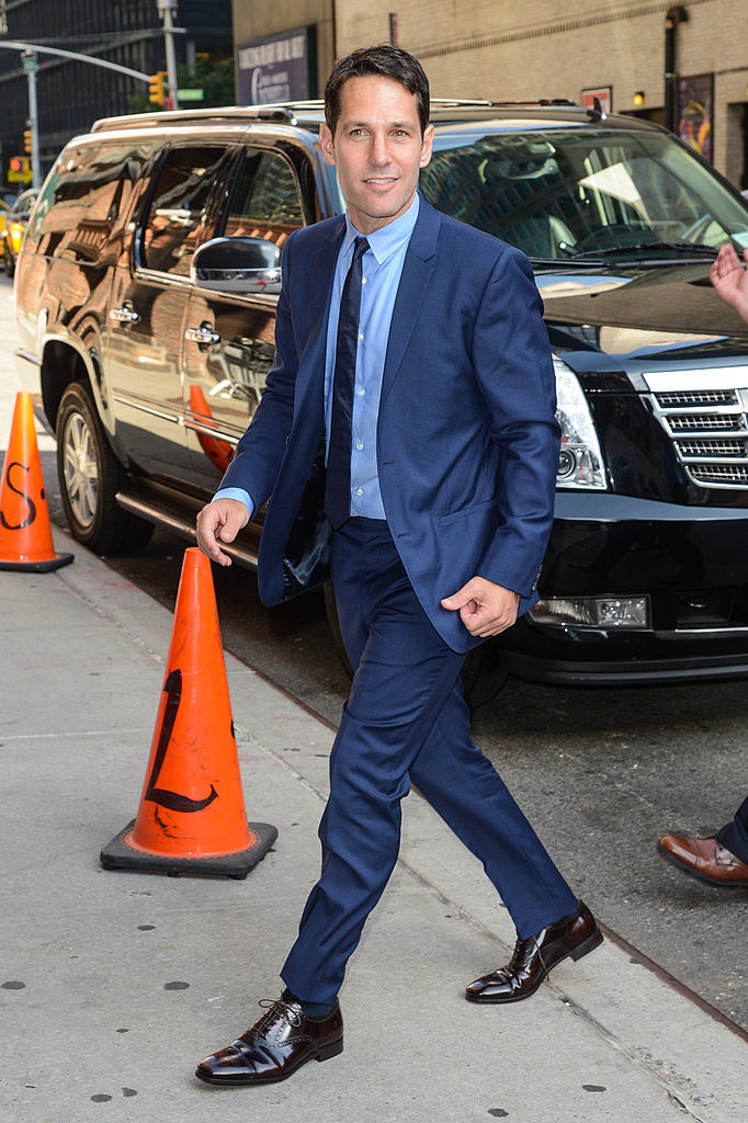 Paul in a suit walking onto a sidewalk