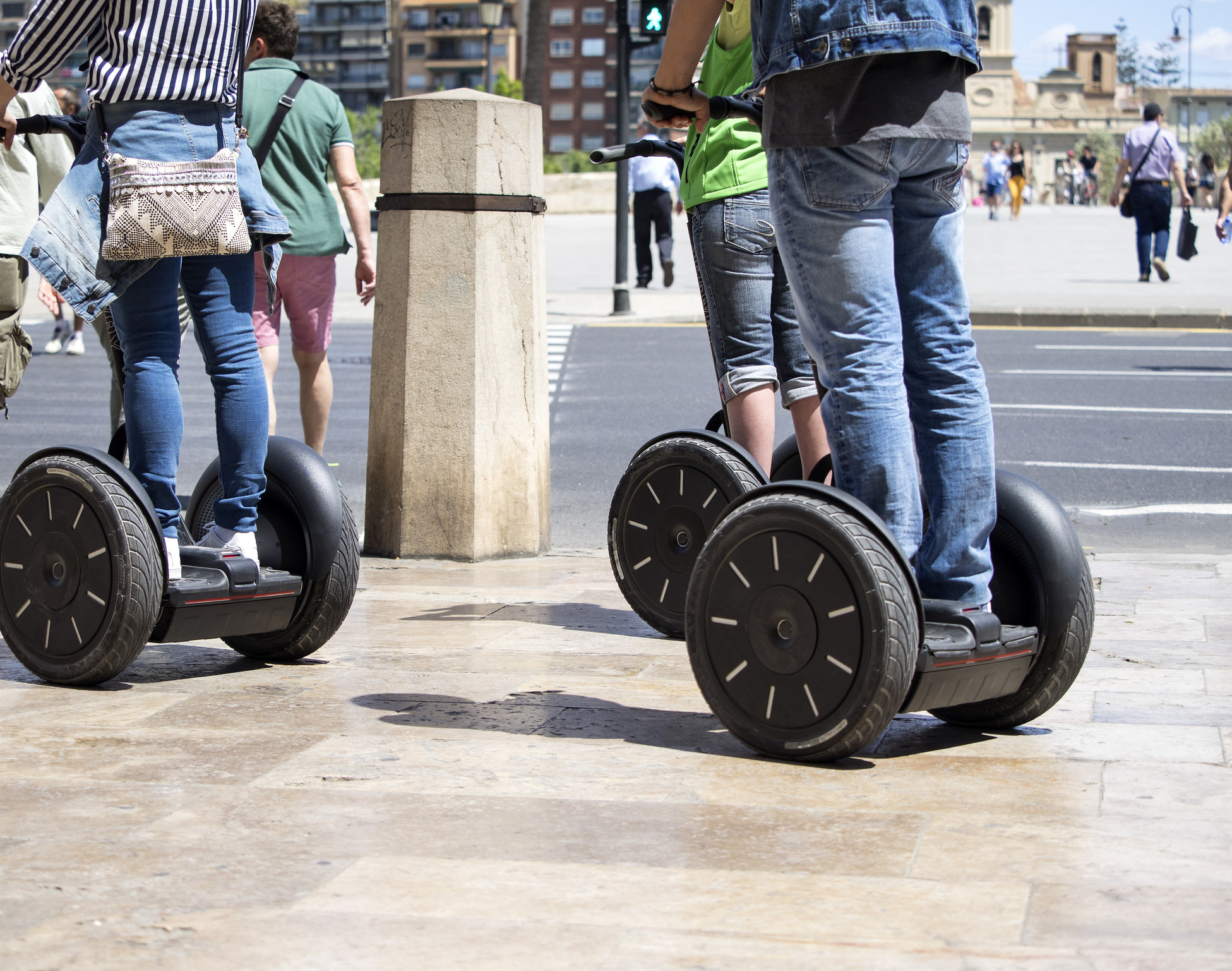 A group of people ride segways on a sidewalk