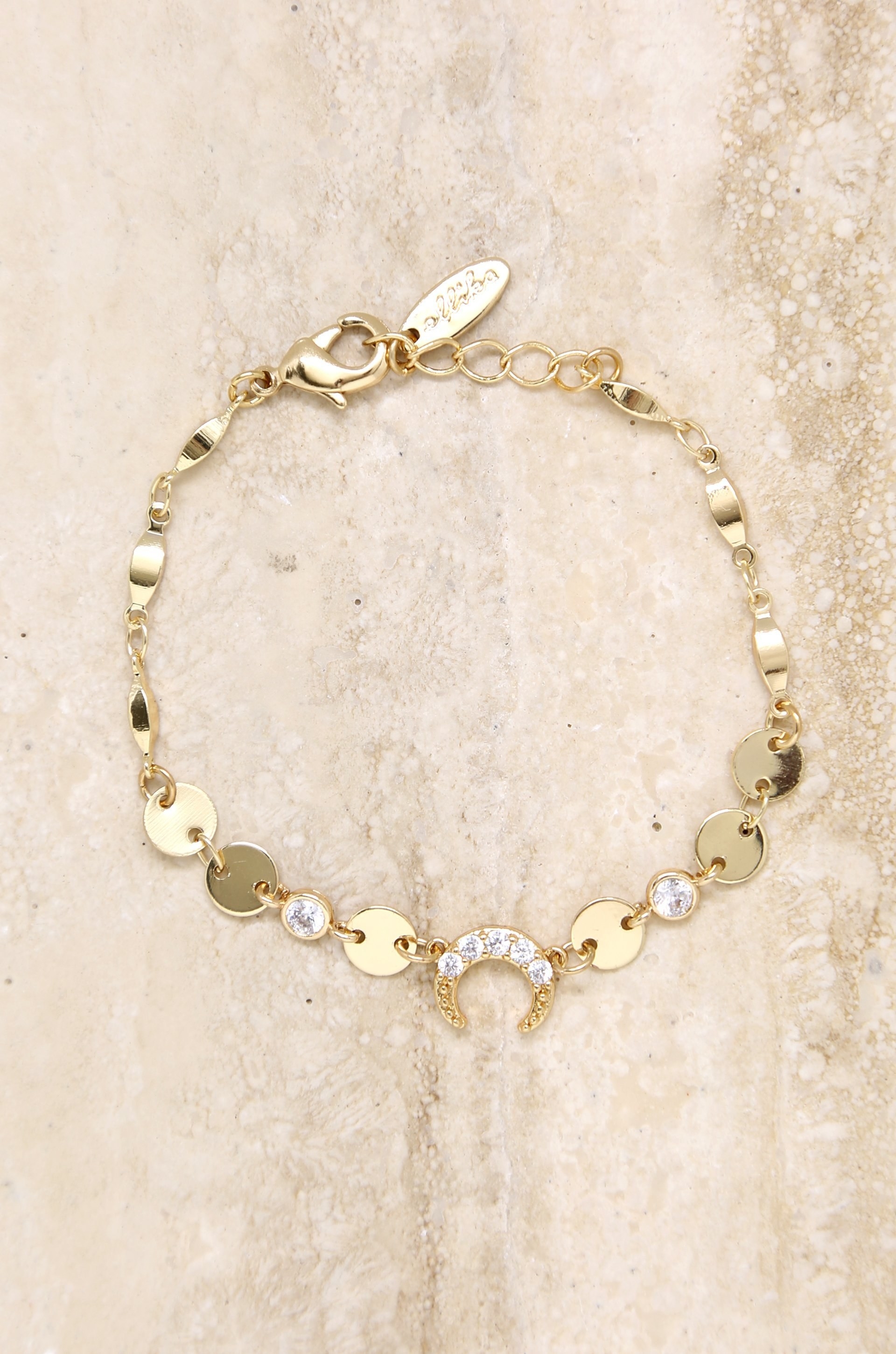 a gold bracelet with gold discs all around and a half moon charm in the middle