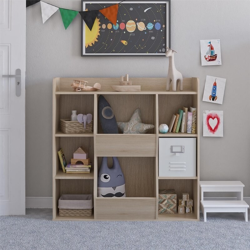 the light wood bookcase with toys, books, and bins