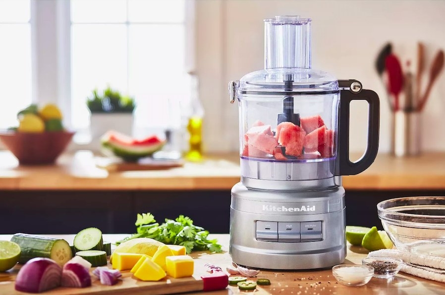 Food processor shown with ingredients inside and around it