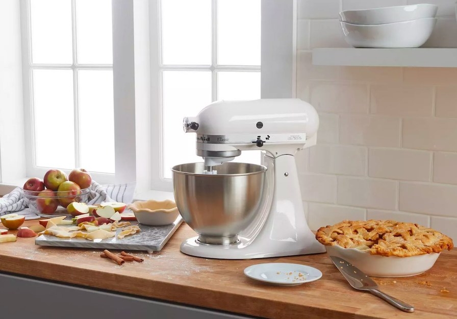 White stand mixer on a butcher block next to a pie and baking ingredients