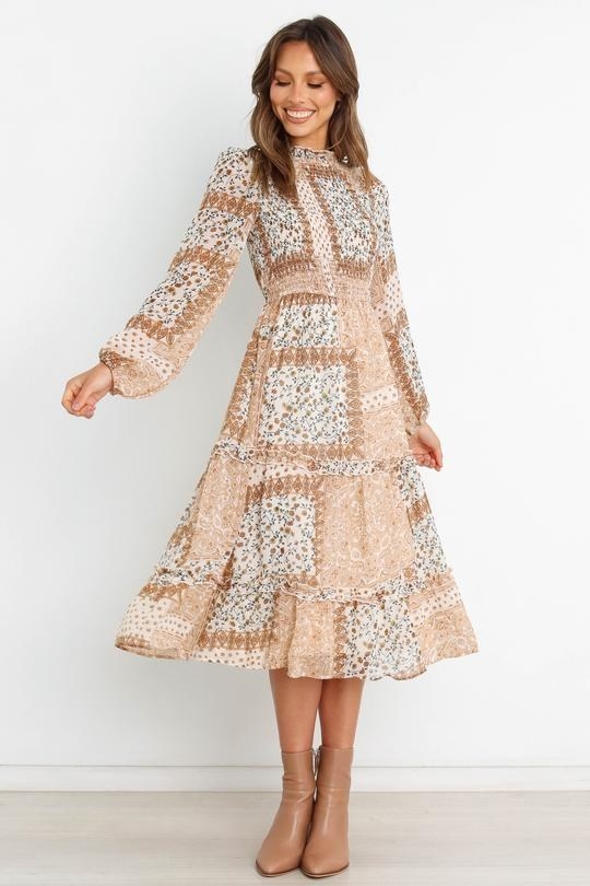 model in tan and white mixed print high neck long sleeve dress