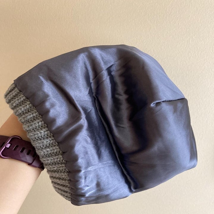 a reviewer showing the satin-lining of the gray beanie