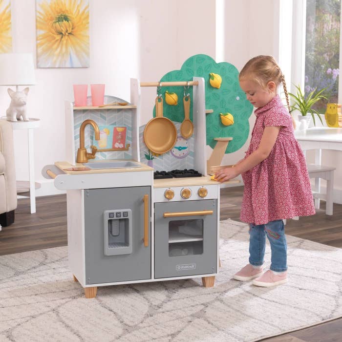A little girl plays with the toy kitchen
