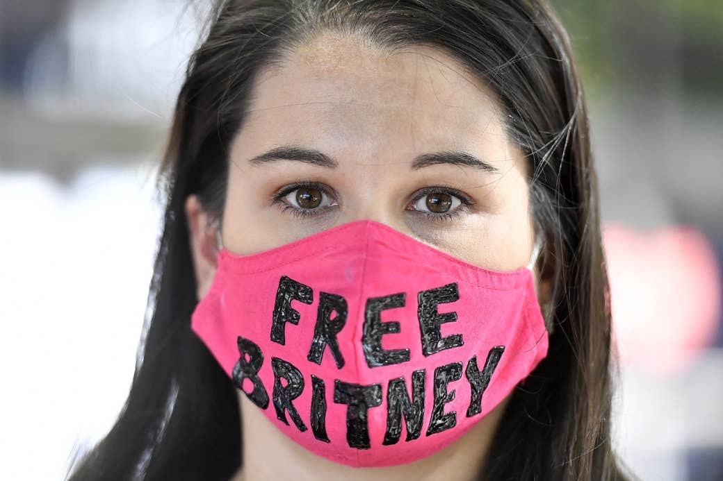A woman wears a pink &quot;Free Britney&quot; mask
