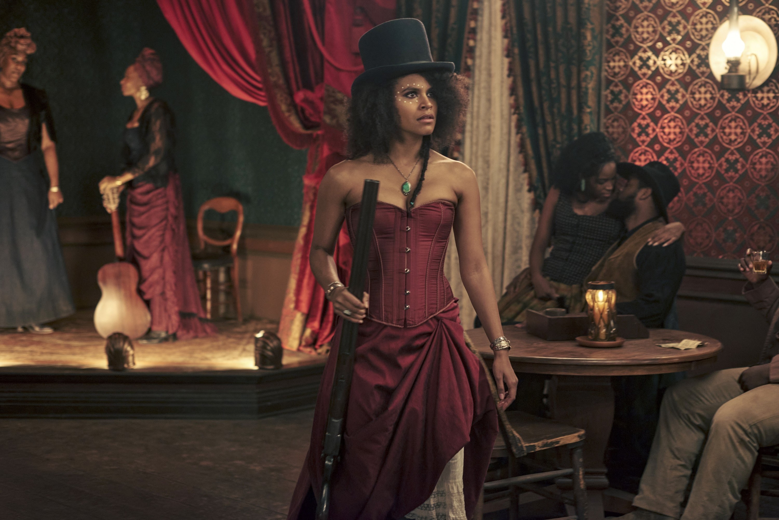 Zazie Beetz as Stagecoach Mary holding a gun as she stands on a dancefloor