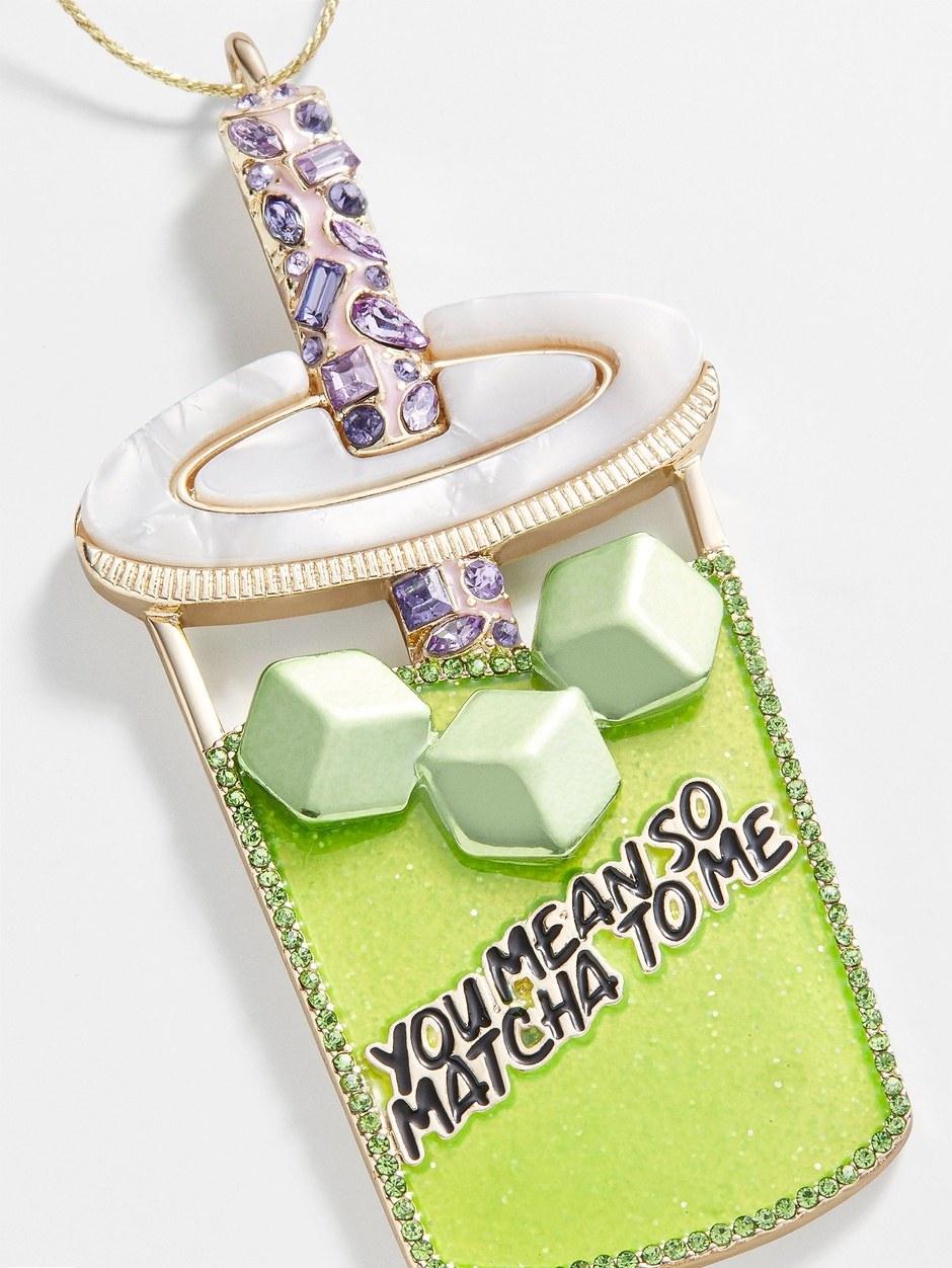 a glittering matcha drink-shaped ornament with &quot;you mean so matcha to me&quot; on it