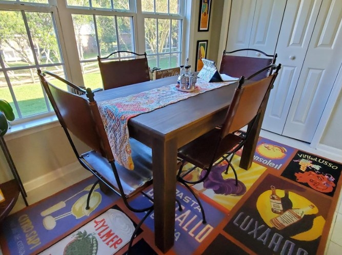A reviewer&#x27;s image of a wooden dining room table that is available in 12 sizes and 10 color options