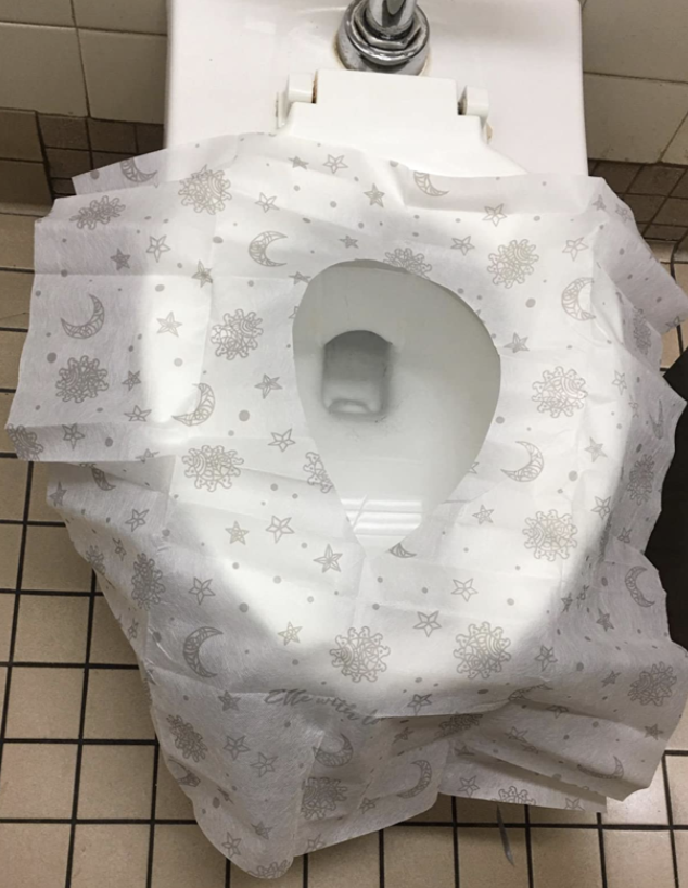 reviewer image of a public toilet seat covered. the entire lid and the bottom of the tank are covered with the product.