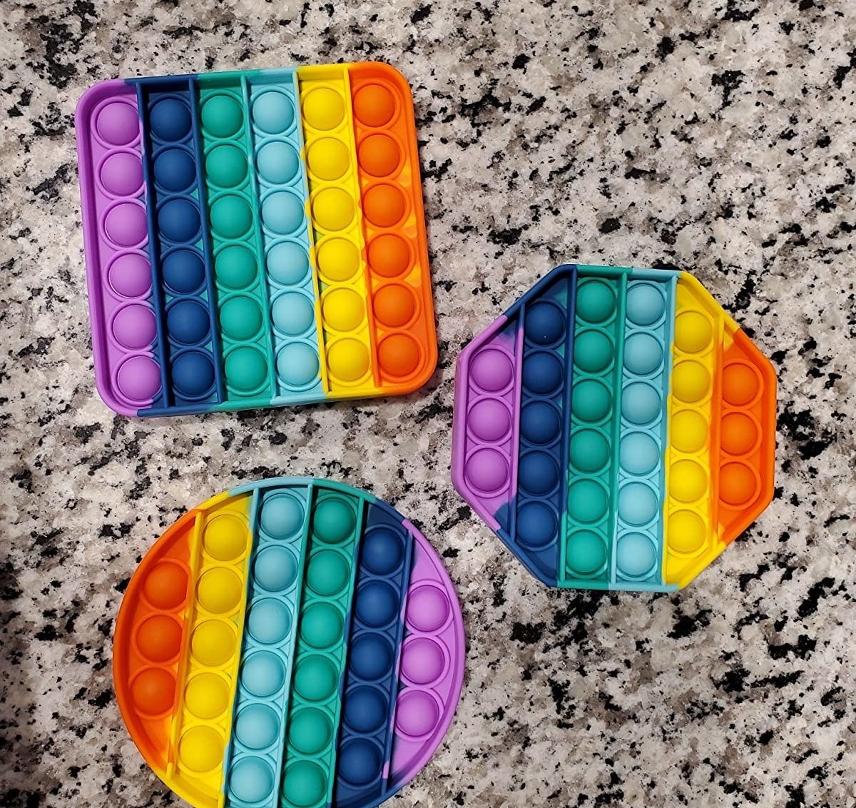 Reviewer&#x27;s image of rainbow-colored circle, square, and octagon fidget toys
