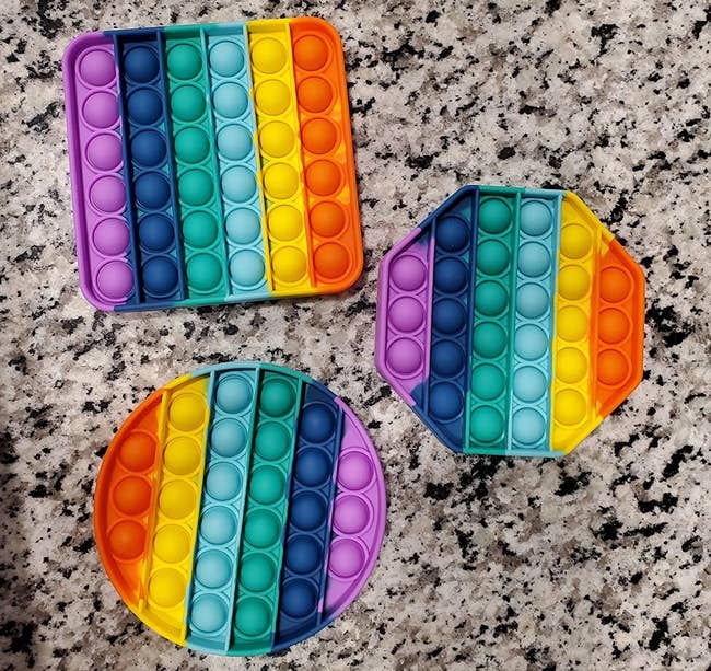 Reviewer's image of rainbow-colored circle, square, and octagon fidget toys