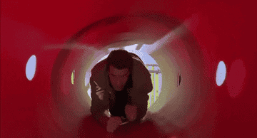 Arnold Schwarzeneggar crawls through a red plastic tube