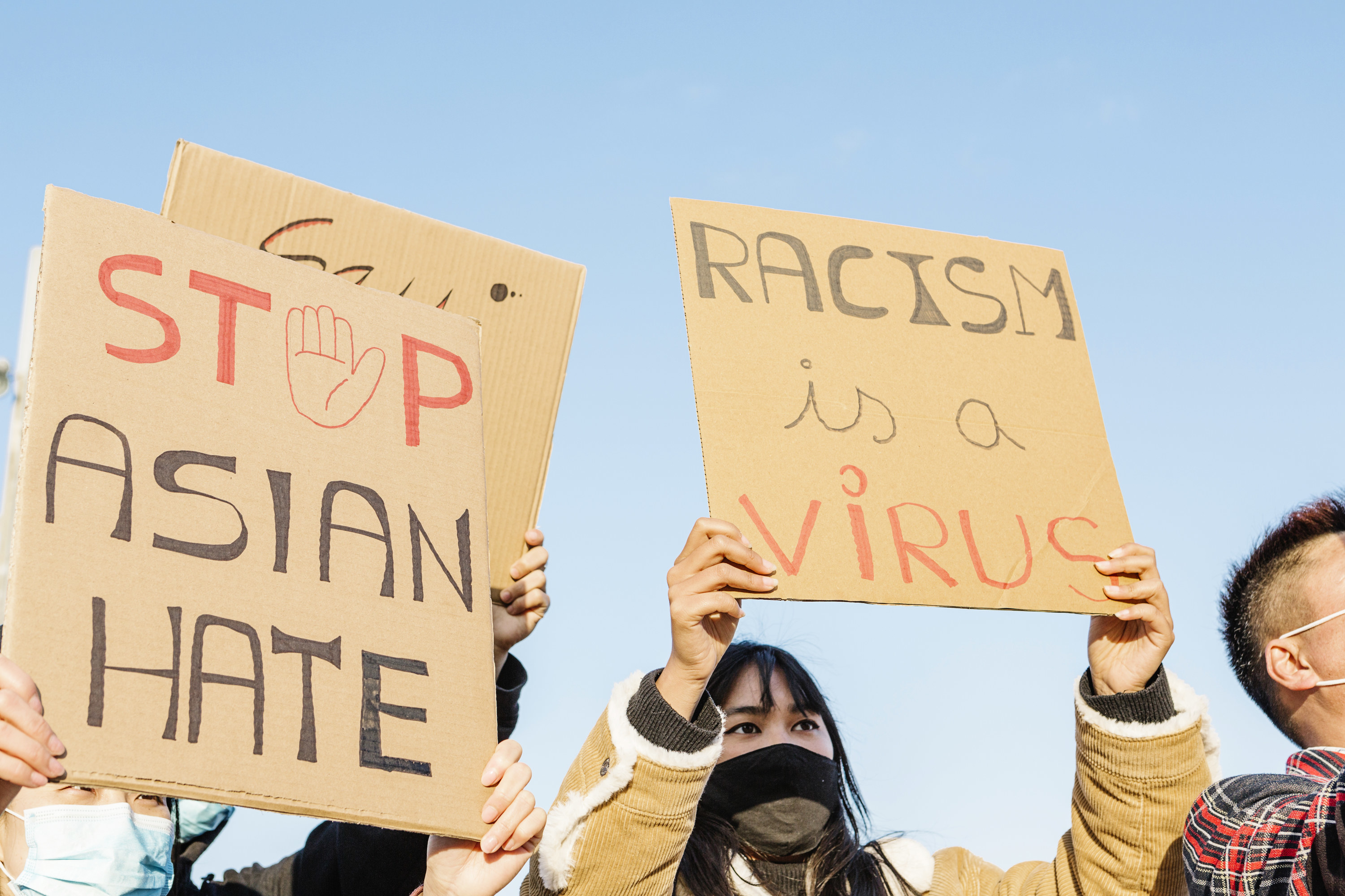 Protesters hold up signs that say stop Asian hate