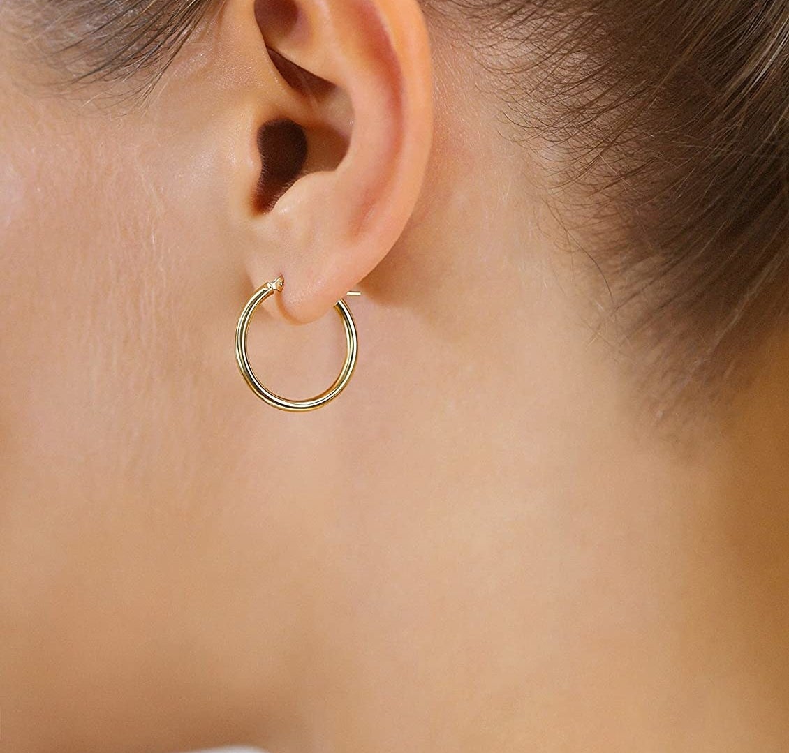 a person wearing the gold hoop earrings