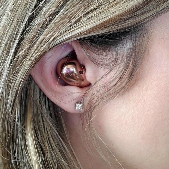 reviewer wearing the gold wireless headphones