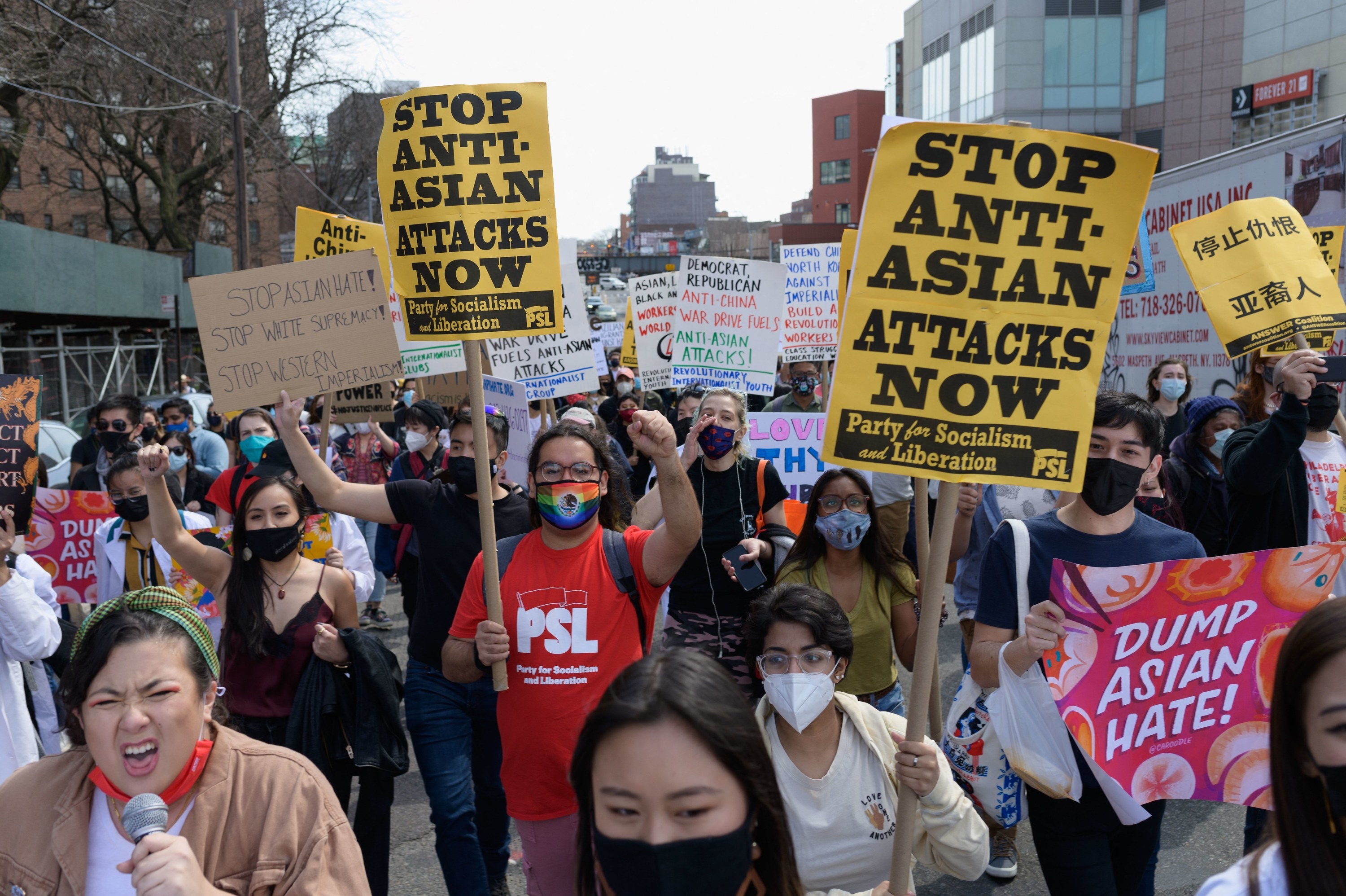 Protesters hold up signs that say stop Asian hate