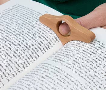 a person holding tan page holder between book pages