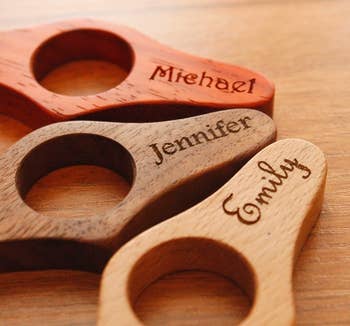 Three personalized page holders in red, dark wood, and tan that are personalized with the names Michael, Jennifer, and Emily