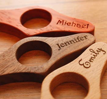 Three personalized page holders in red, dark wood, and tan that are personalized with the names Michael, Jennifer, and Emily