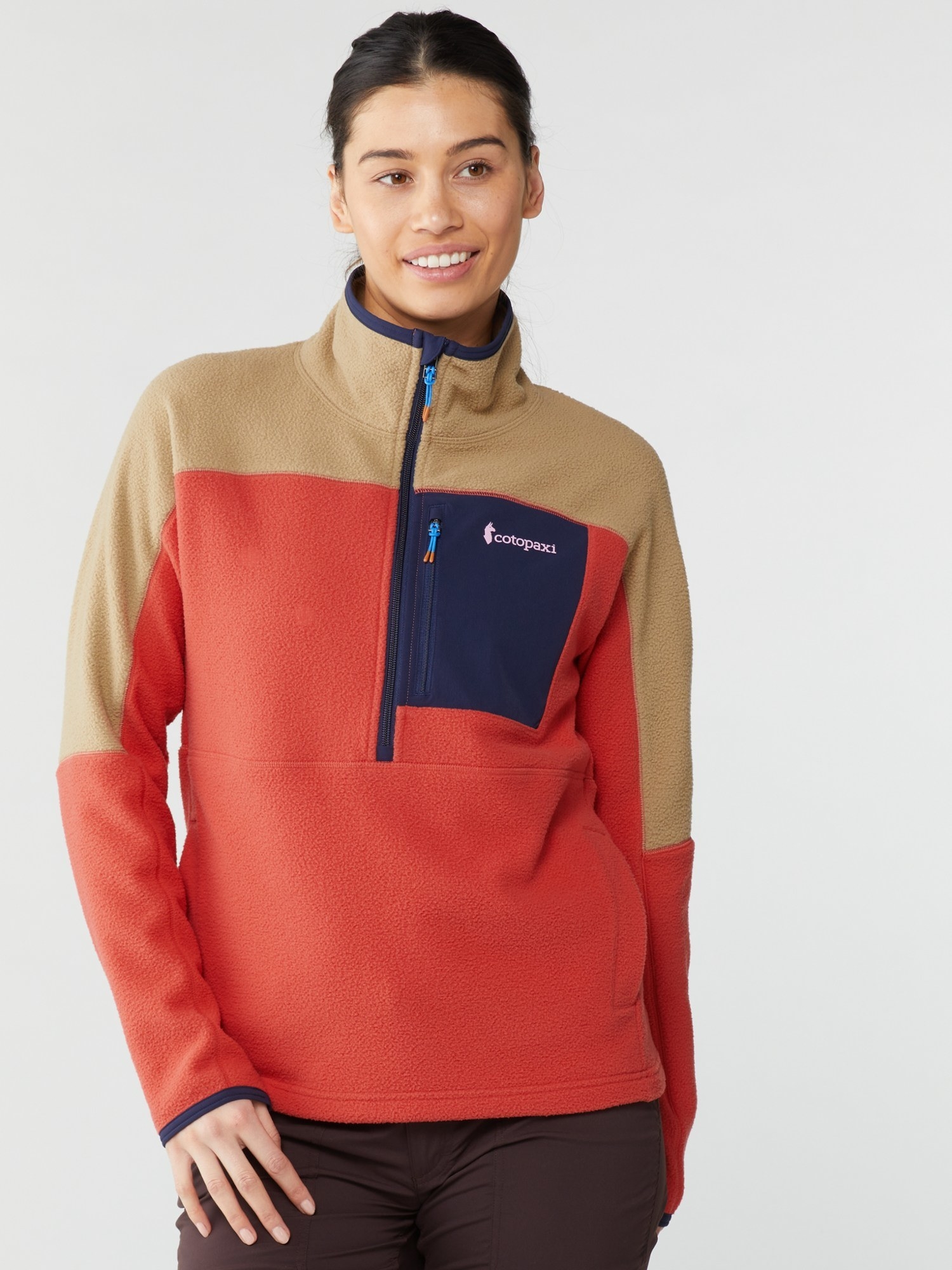 model in the orange, tan, and navy fleece with a large front pocket