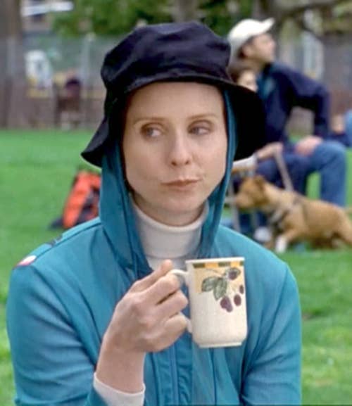 Miranda from the original series sitting in a park drinking from a mug