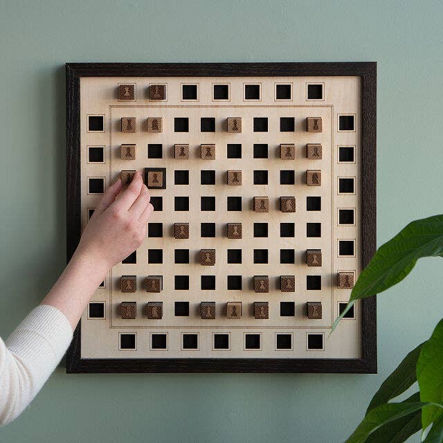 Model moving wooden chess piece on a wall mounted wooden chessboard