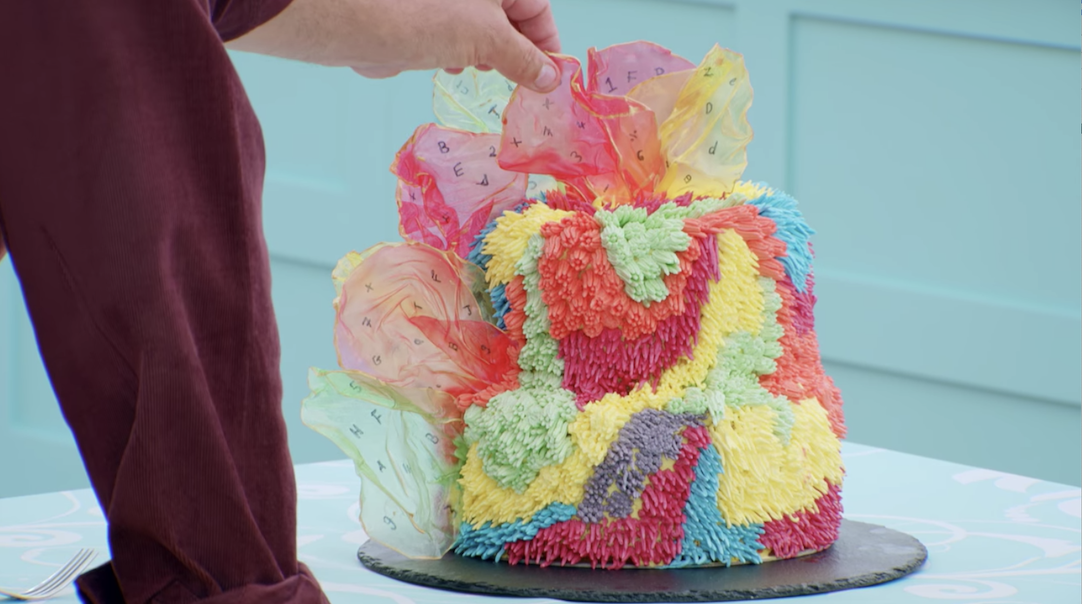 Lizzie&#x27;s rainbow cake, decorated with bits of rice paper decorated with letters and numbers