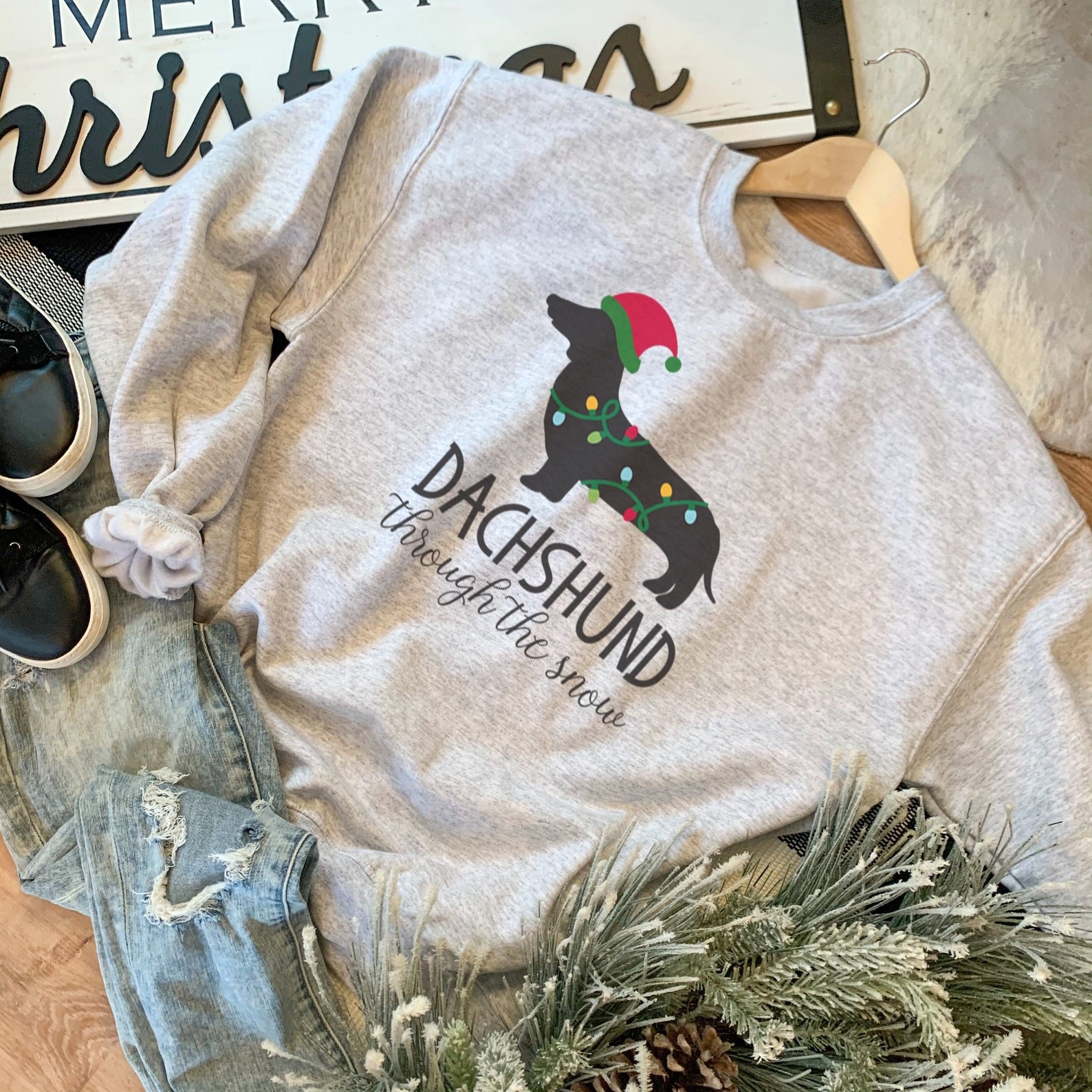 The grey sweatshirt with a dachshund wrapped in Christmas lights and text &quot;dachshund through the snow&quot;