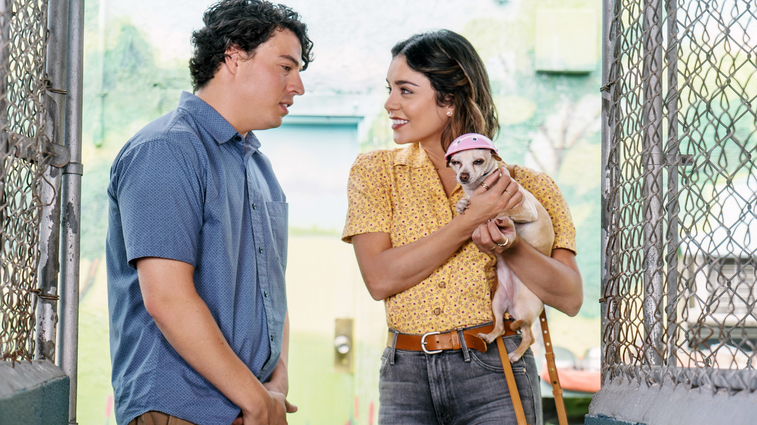 Jon Bass talks to Vanessa Hudgens as she holds a dog