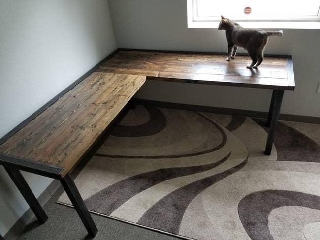 Wood and black L-shaped desk with cat standing on top