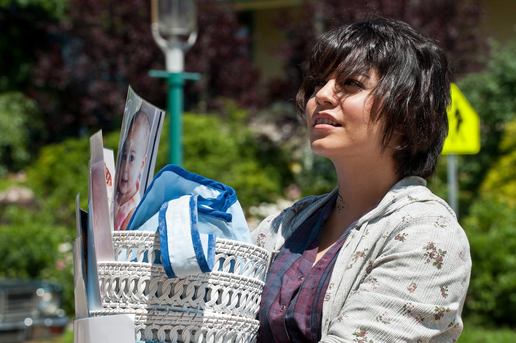 Vanessa Hudgens with messy hair holds a basket of belongings