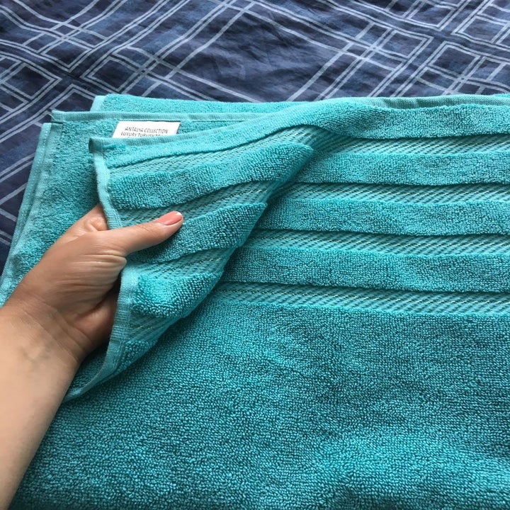 Close-up of a reviewer's hand holding the blue towel to show its texture