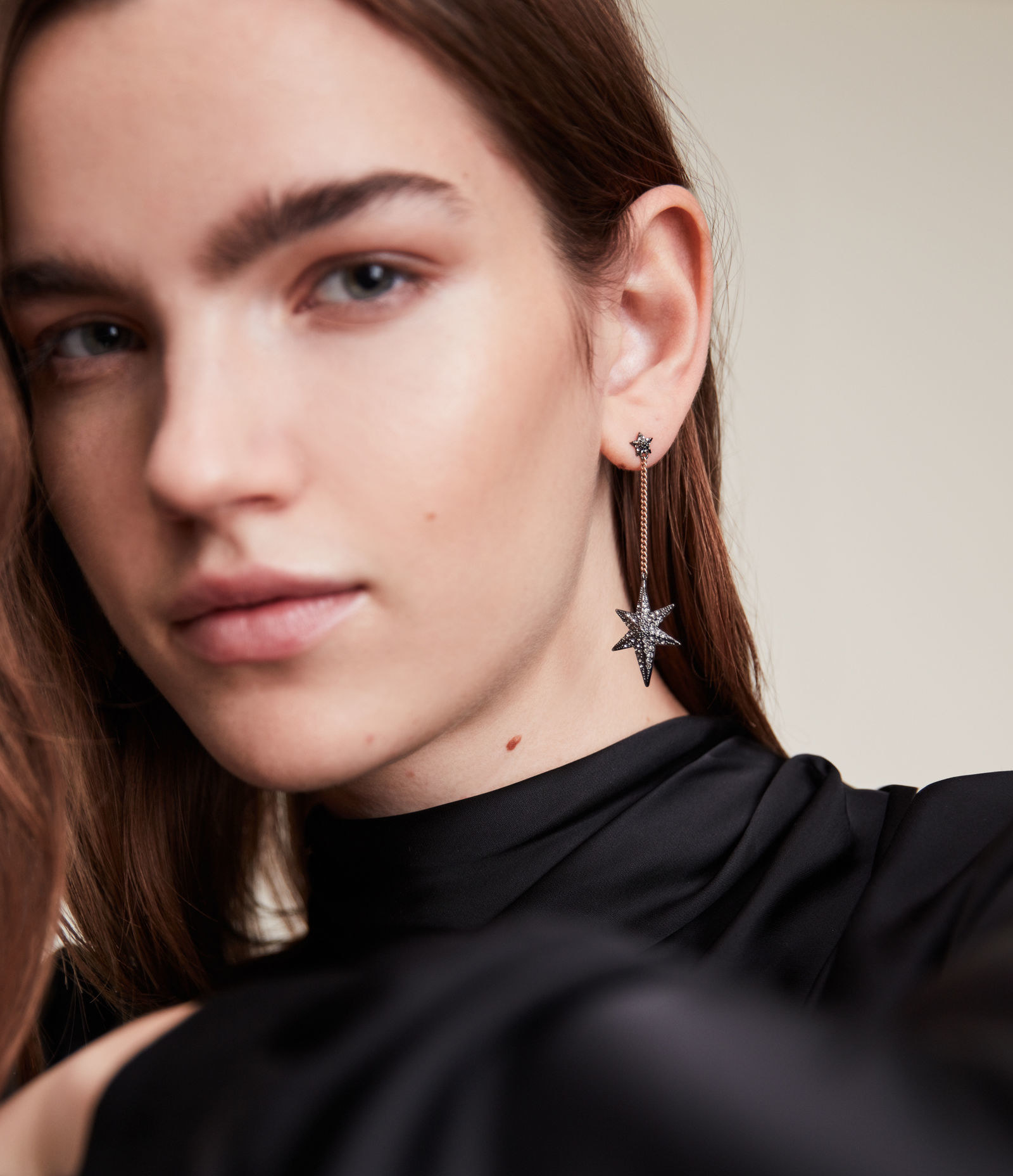 A model with the hematite and gold tone earrings, with a star on the lobe, and another larger star hanging from a dangle chain