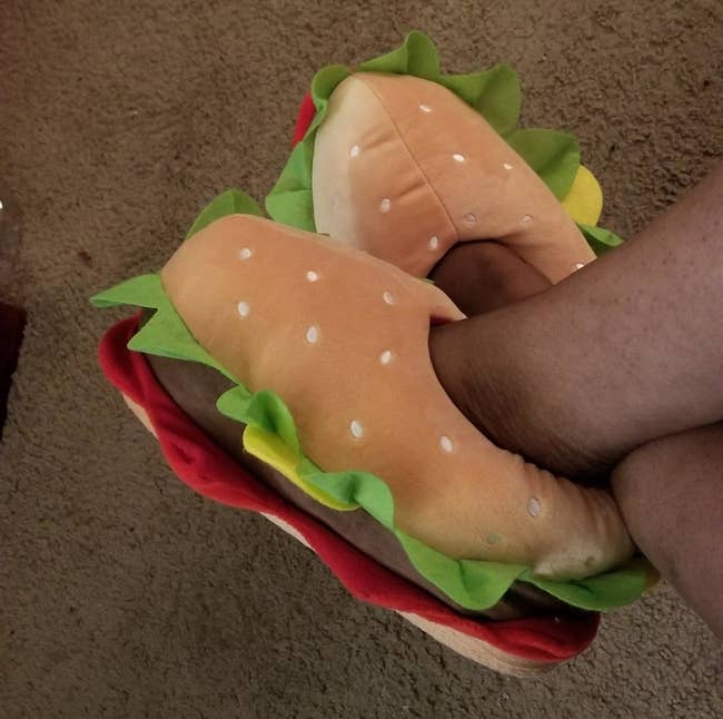 A reviewer in the slippers, which are shaped like hamburgers
