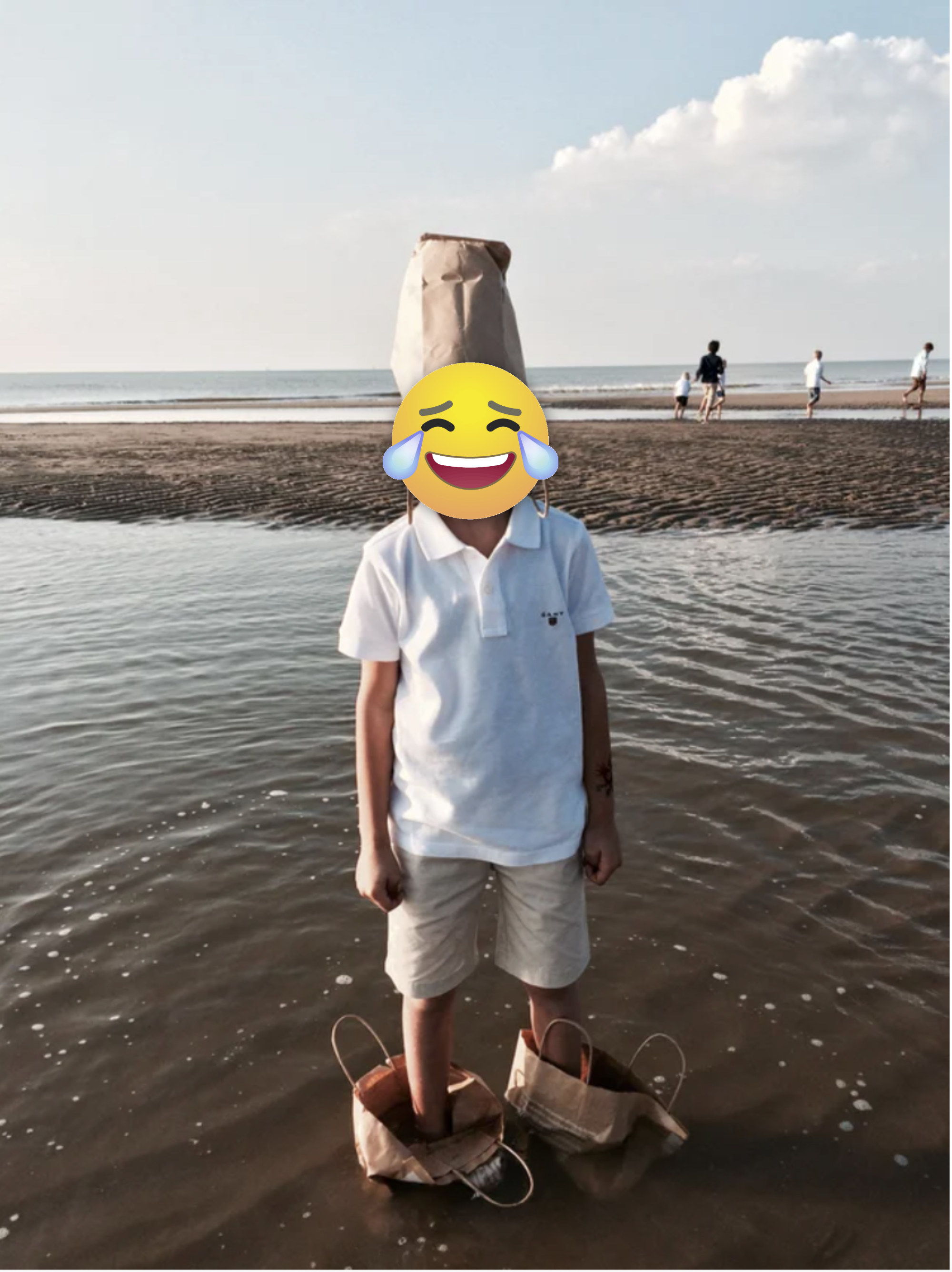 He didn&#x27;t want his shoes to get wet, so he put paper bags on his feet and waded into the ocean.A kid stands with this shoes in paper bags in the river