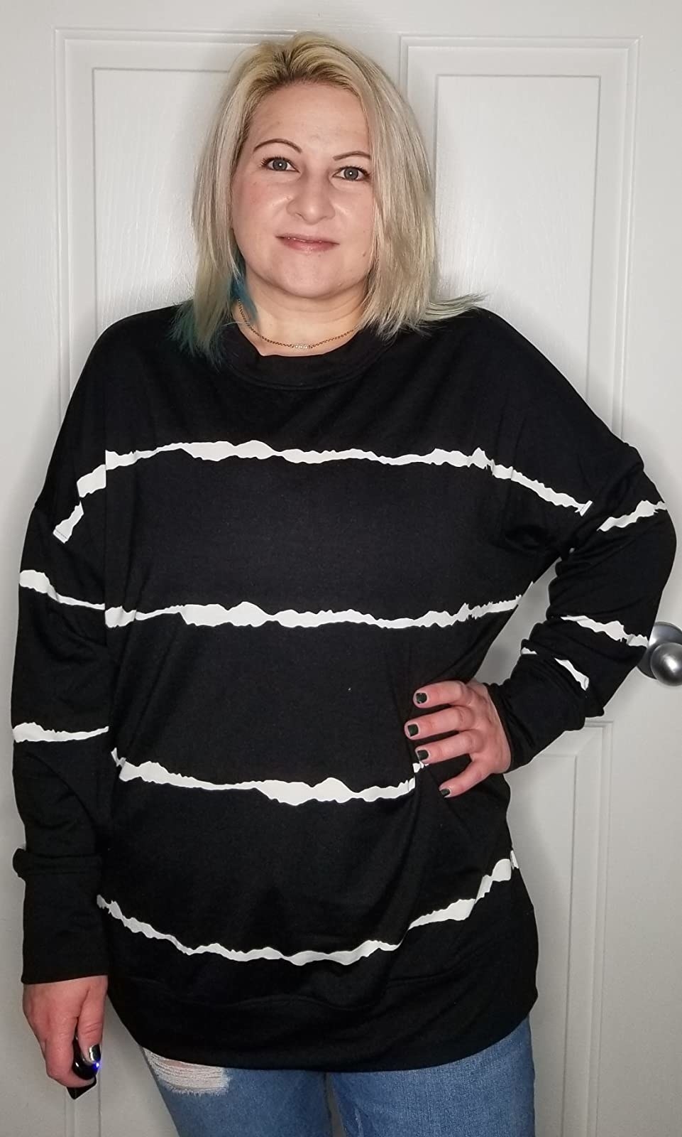 a reviewer in a long sleeve black top with white vertical squiggly stripes