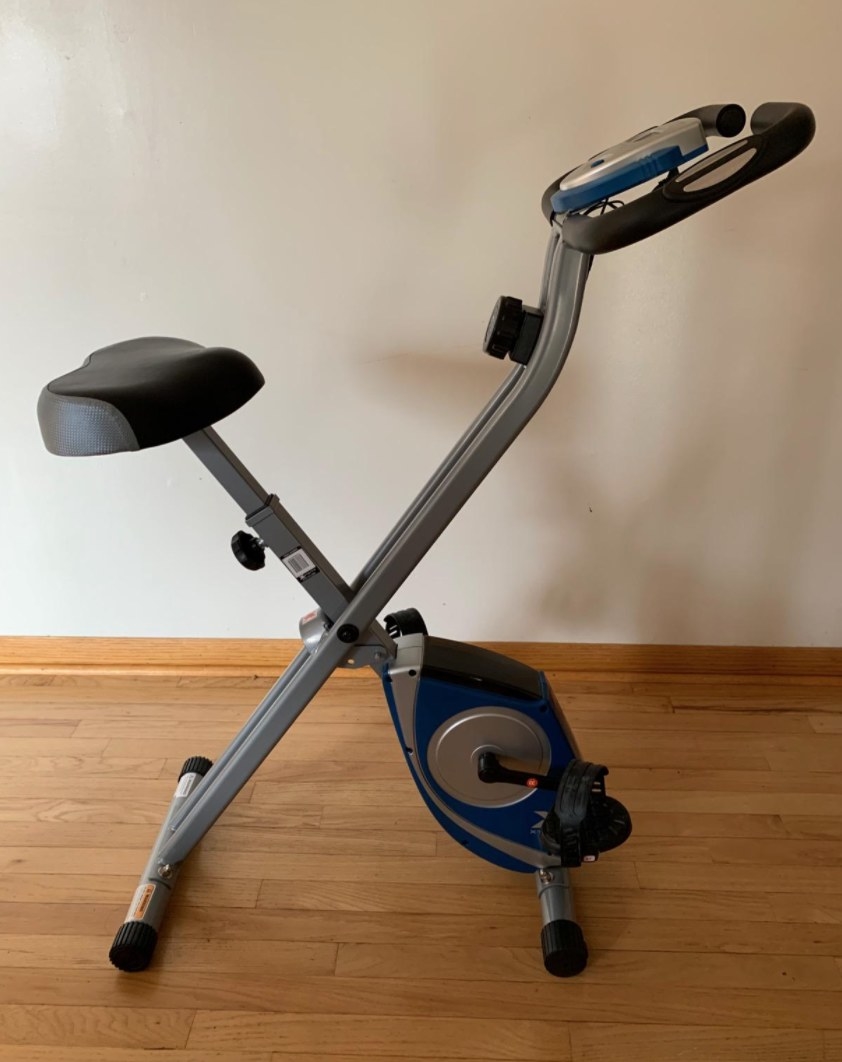 Reviewer&#x27;s black and blue folding stationary bike with screen