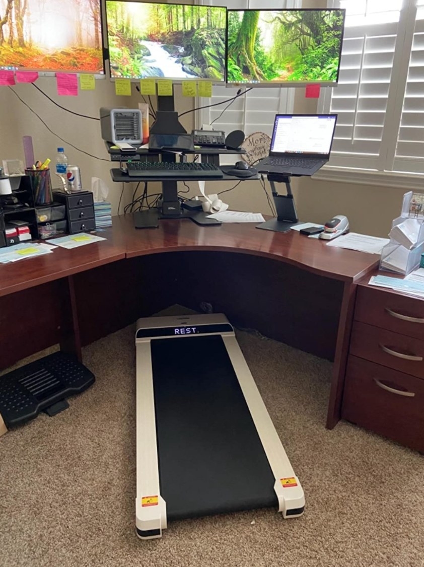 A reviewer&#x27;s mini white treadmill under desk without handholds