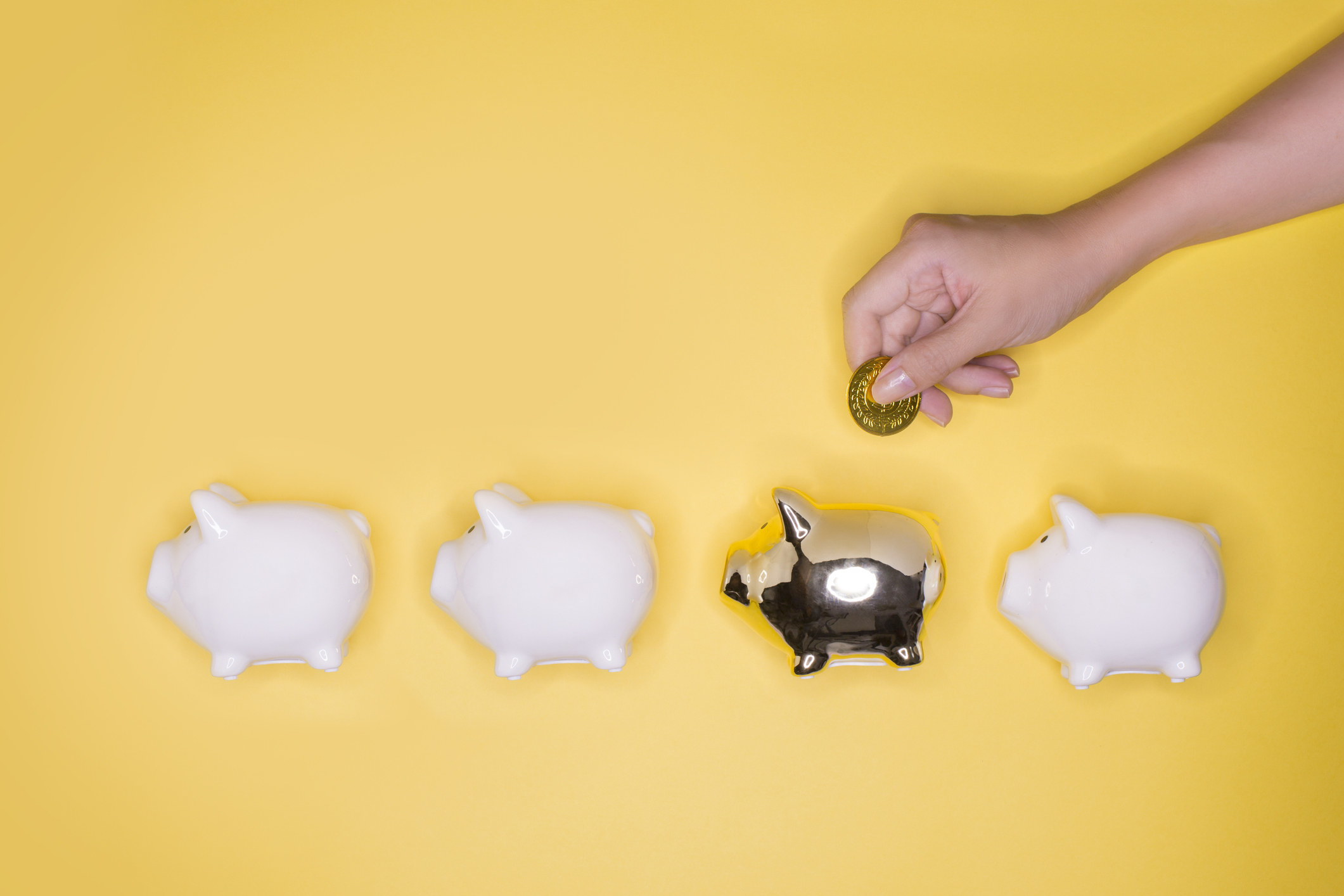 Hand putting coin into a golden piggy bank.